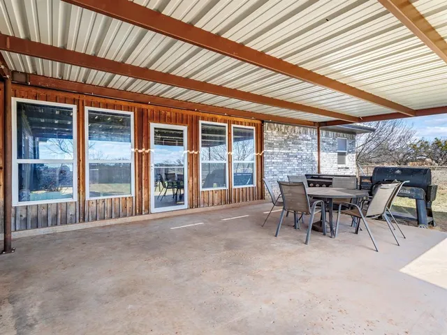 a view of a patio with table and chairs next to a yard