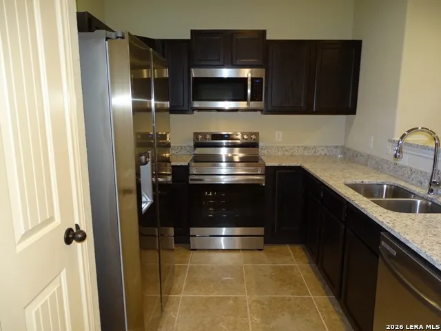 a kitchen with stainless steel appliances granite countertop a refrigerator and a stove top oven