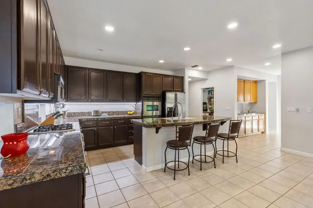 a kitchen with stainless steel appliances granite countertop a stove a sink a oven a dining table and chairs