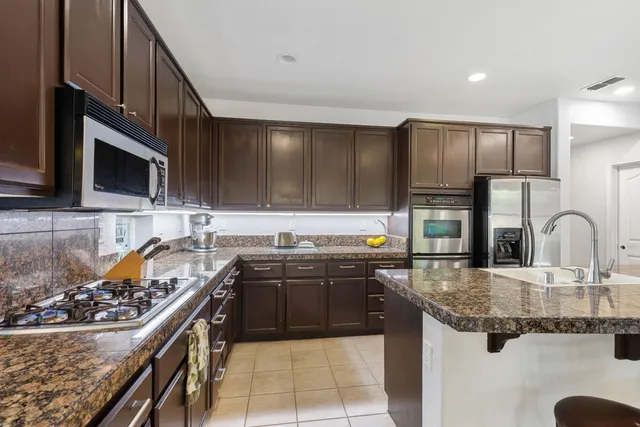 a kitchen with kitchen island granite countertop a sink stainless steel appliances and cabinets
