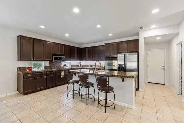 a kitchen with stainless steel appliances granite countertop a refrigerator and a stove top oven