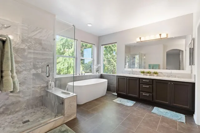 a spacious bathroom with a tub sink shower and mirror