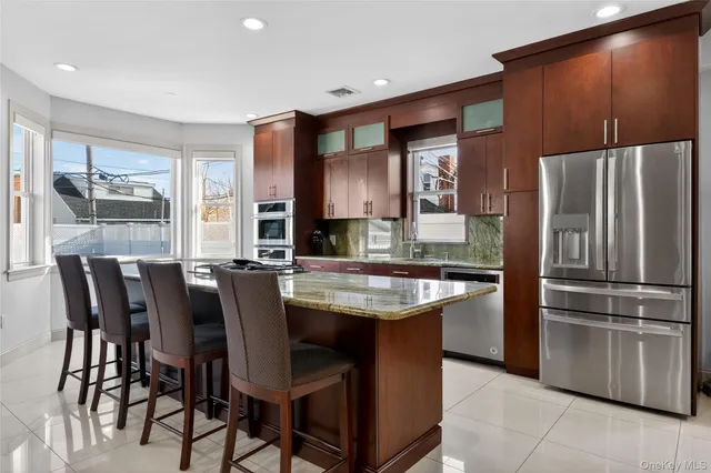 a large kitchen with stainless steel appliances kitchen island granite countertop a table chairs in it and a window