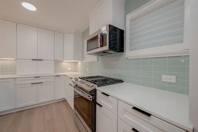 a kitchen with stainless steel appliances white cabinets and a stove top oven