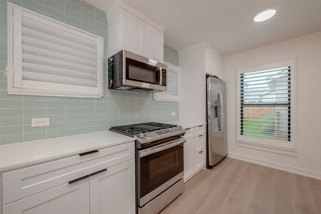 a kitchen with white cabinets stainless steel appliances and wooden floor