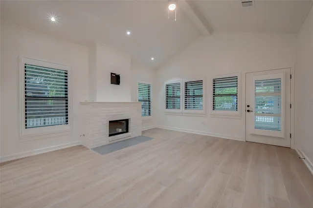 an empty room with windows and fireplace
