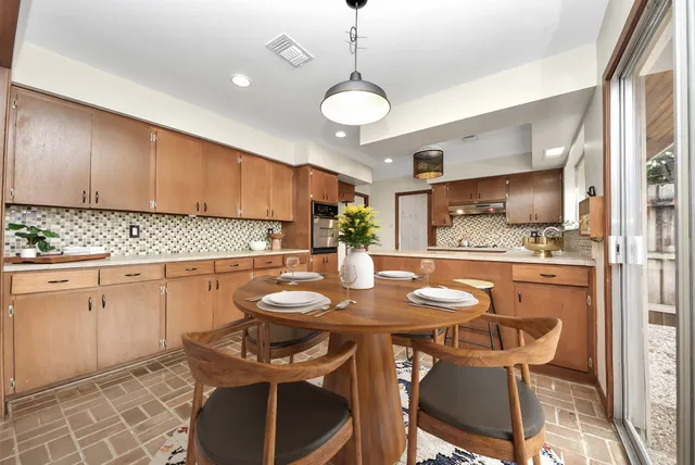 a kitchen with stainless steel appliances granite countertop a sink a stove a dining table and chairs