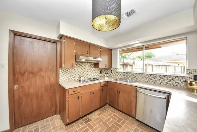 a kitchen with a sink dishwasher a stove and white appliances with wooden floor