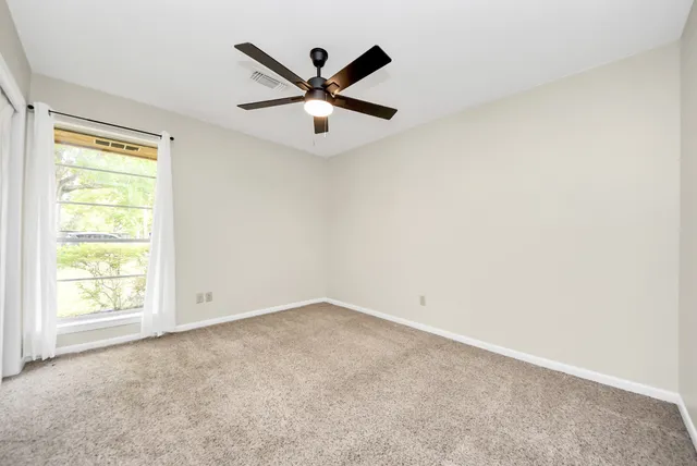 an empty room with a window and a fan