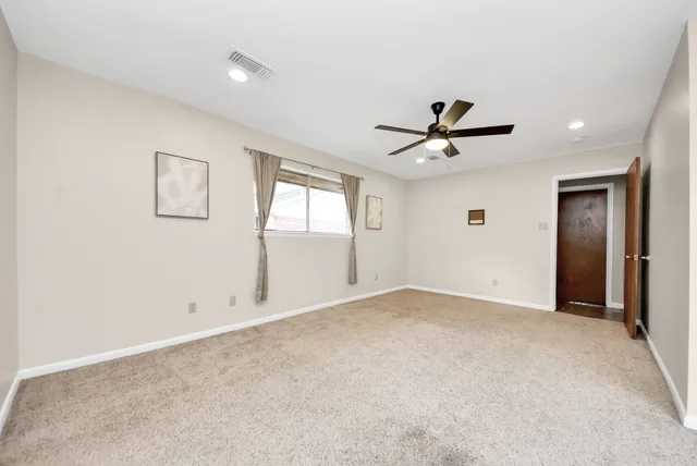 an empty room with window and ceiling fan