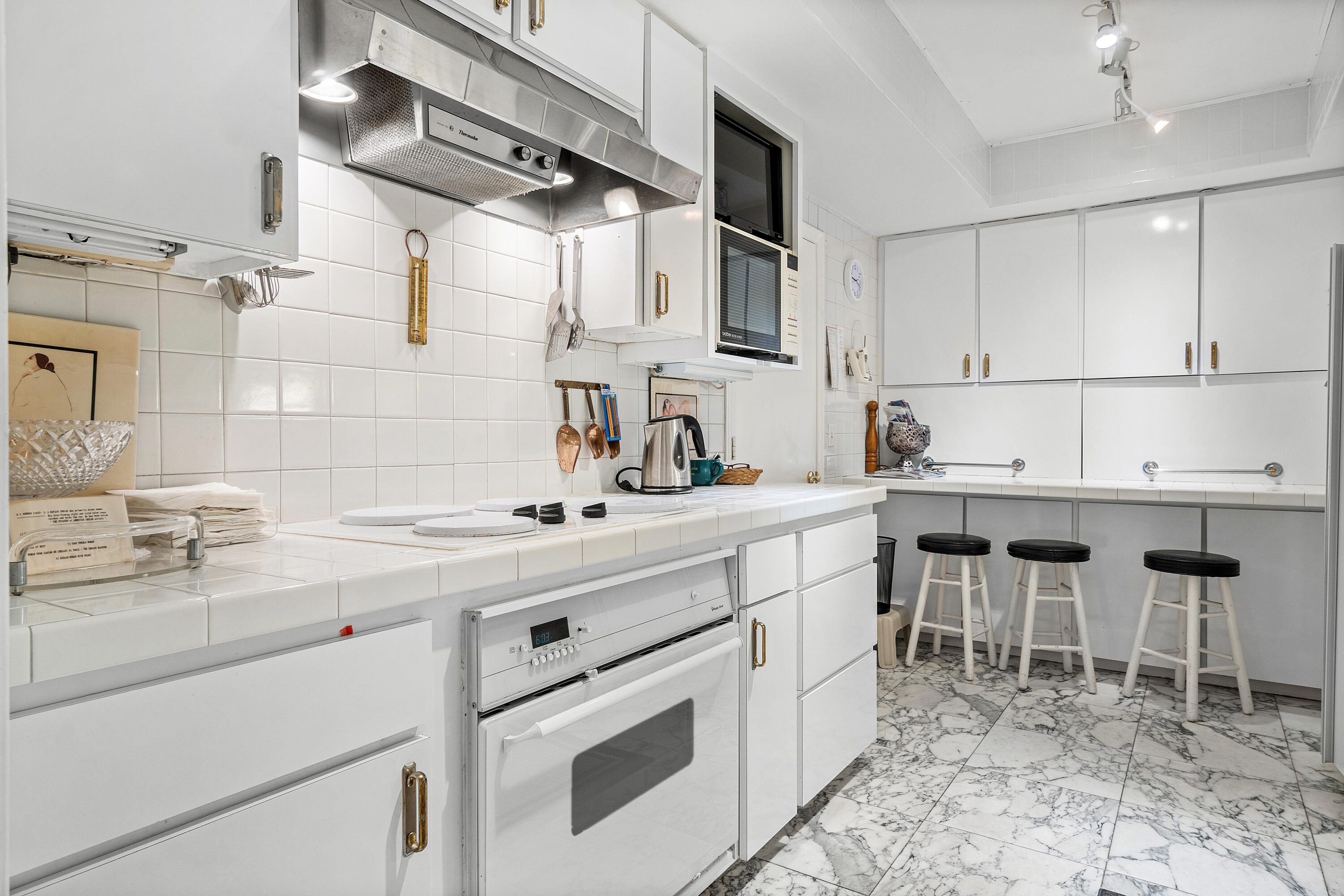 150 Bradley Place, Unit 101 Palm Beach, FL 33480 - Photo 7 of 38 a kitchen with appliances cabinets and chairs