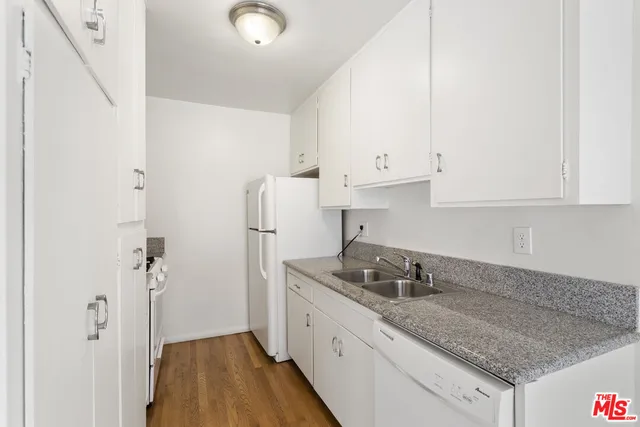a kitchen with granite countertop white cabinets and a sink
