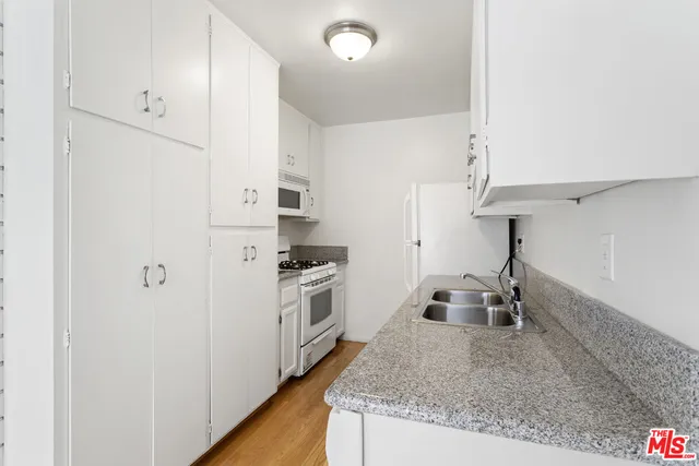 a kitchen with granite countertop a sink a stove and refrigerator