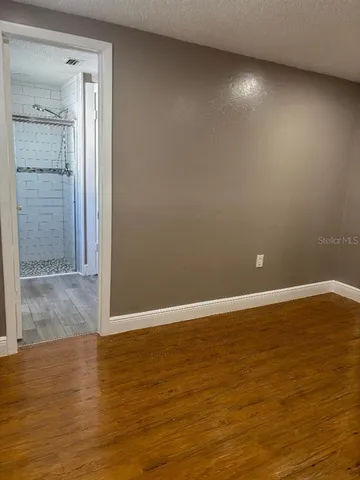 a view of an empty room with wooden floor and closet