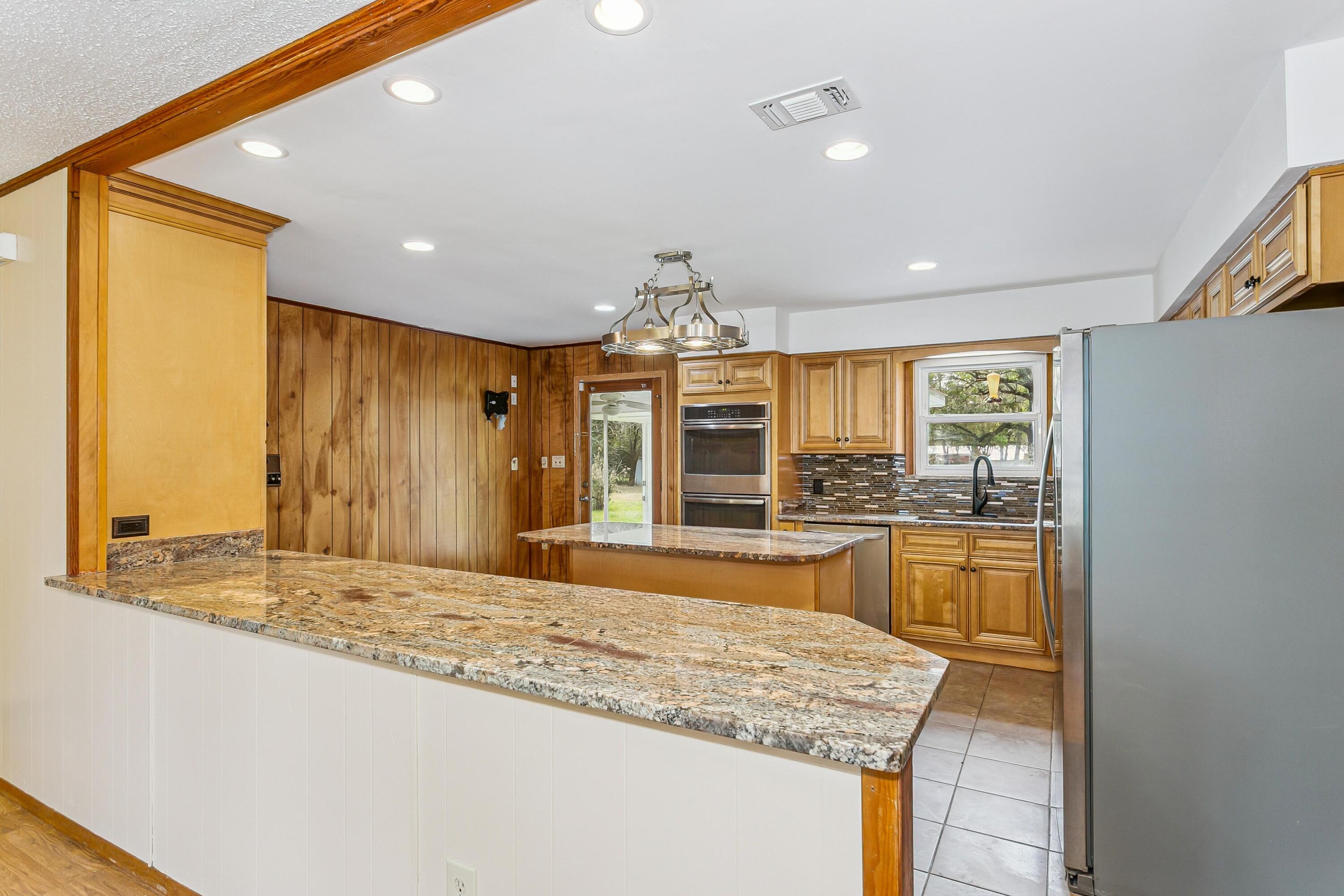 3146 Forrest Avenue Crestview, FL 32539 - Photo 11 of 47 a large kitchen with kitchen island granite countertop wooden cabinets and a granite counter tops