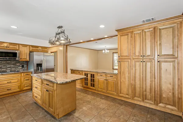 a kitchen with stainless steel appliances granite countertop a stove top oven a sink and a refrigerator