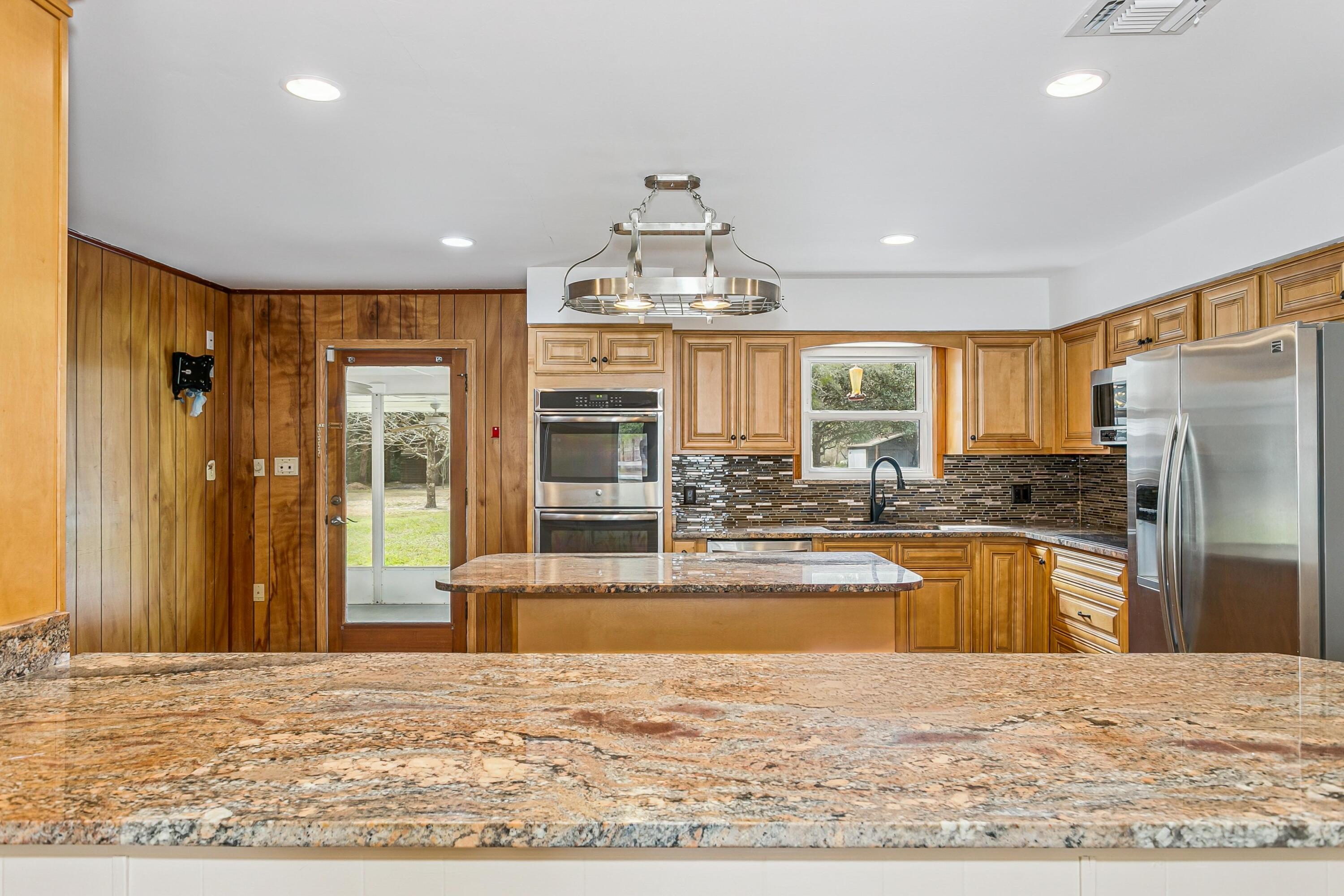 3146 Forrest Avenue Crestview, FL 32539 - Photo 15 of 47 a large kitchen with kitchen island granite countertop a refrigerator stove top oven and sink