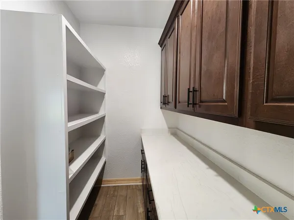 a view of a hallway with wooden floor and a bathroom