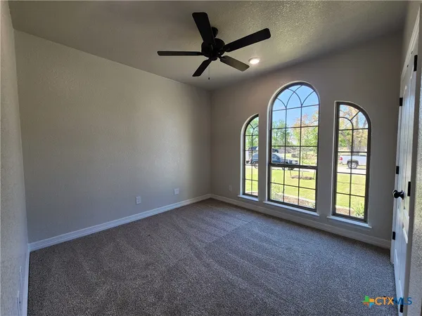 an empty room with a ceiling fan and windows