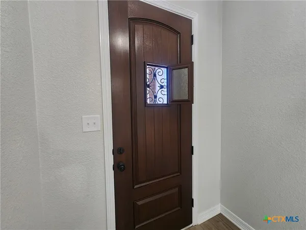 a view of a hallway with wooden floor and a chandelier