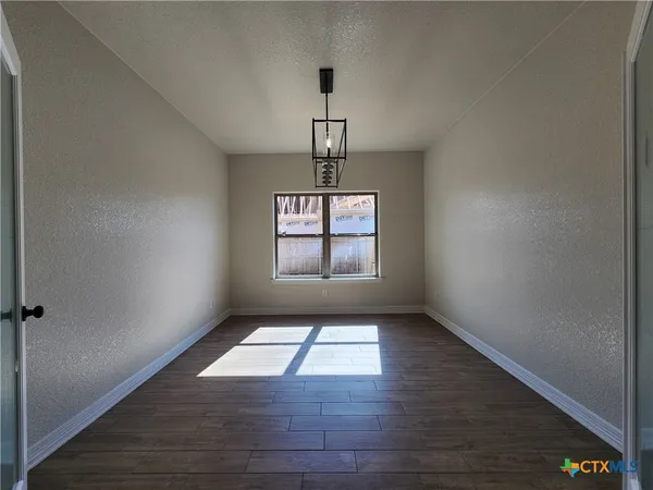 a view of empty room with fireplace and wooden floor