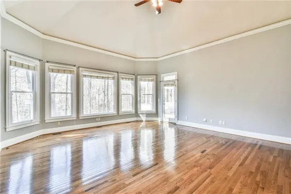 an empty room with wooden floor and windows