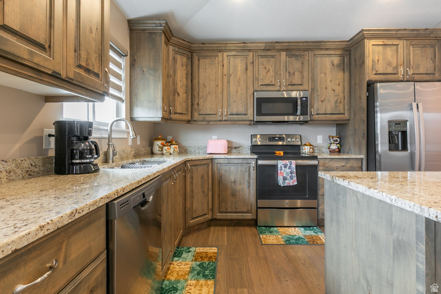 1228 North Providence Way Tooele, UT 84074 - Photo 10 of 28 Kitchen featuring wood-finish cabinetry, granite countertops, a stainless steel sink with a gooseneck faucet, a stainless steel dishwasher, and stainless steel appliances including a microwave, range, and side-by-side refrigerator