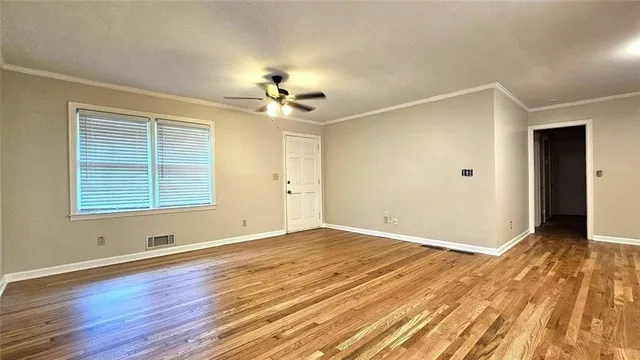 a view of an empty room with wooden floor and a window