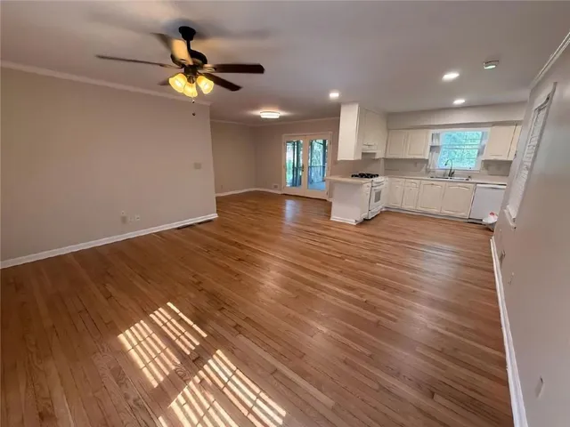 a view of kitchen and empty room with wooden floor