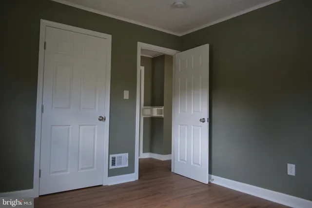 an empty room with wooden floor & closet area