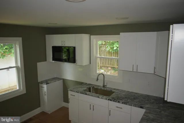 a kitchen with granite countertop a sink and a stove top oven