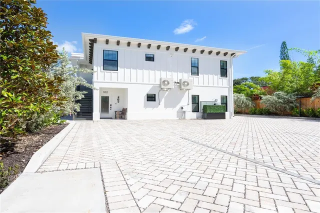 a view of a white house with a small yard and potted plants
