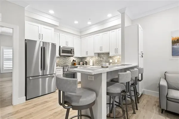 a kitchen with stainless steel appliances granite countertop a dining table chairs refrigerator and cabinets