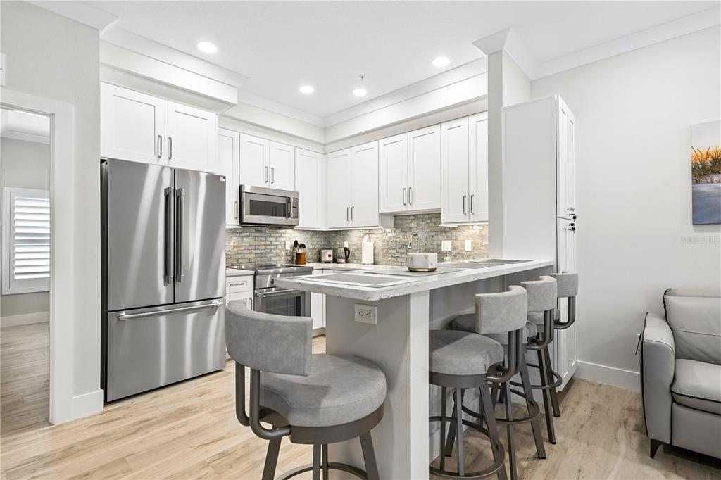1234 15th Street, Unit 102 Sarasota, FL 34236 - Photo 9 of 30 a kitchen with stainless steel appliances granite countertop a dining table chairs refrigerator and cabinets