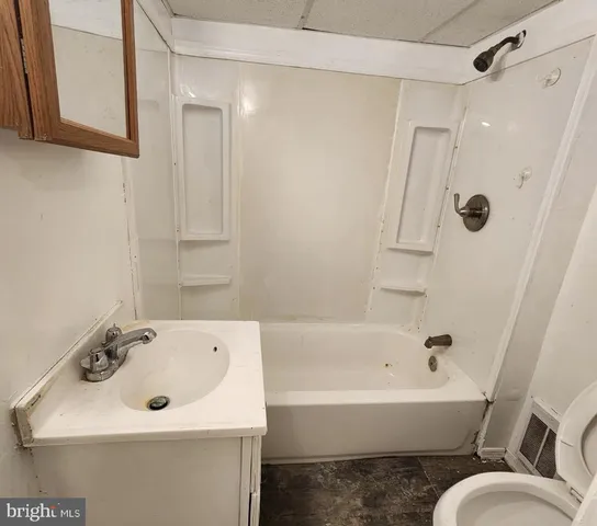 a bathroom with a bathtub shower sink vanity and toilet