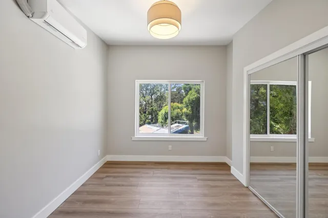 a view of an empty room with wooden floor and a window
