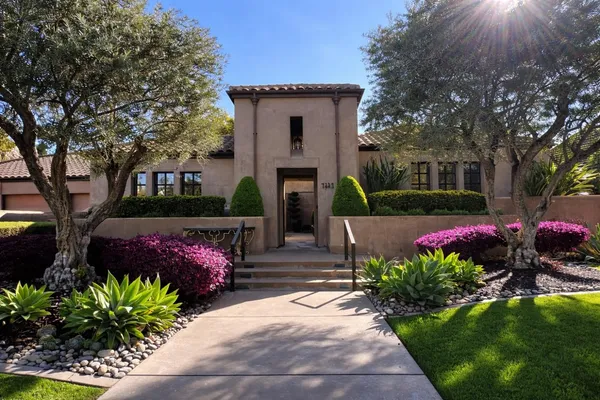 a front view of a house with lots of flowers and trees