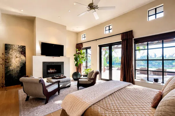 a bedroom with a bed large window and a flat tv screen