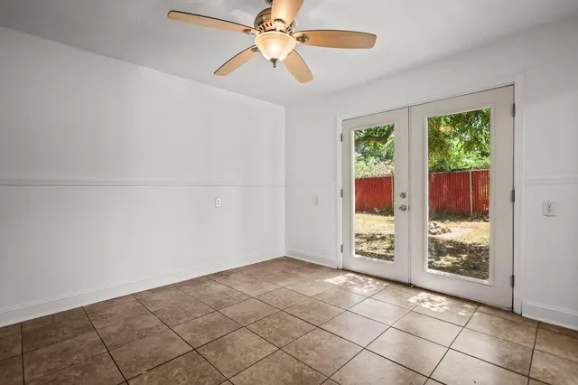 a view of an empty room with window and chandelier fan