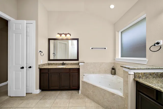 a bathroom with a tub sink and mirror
