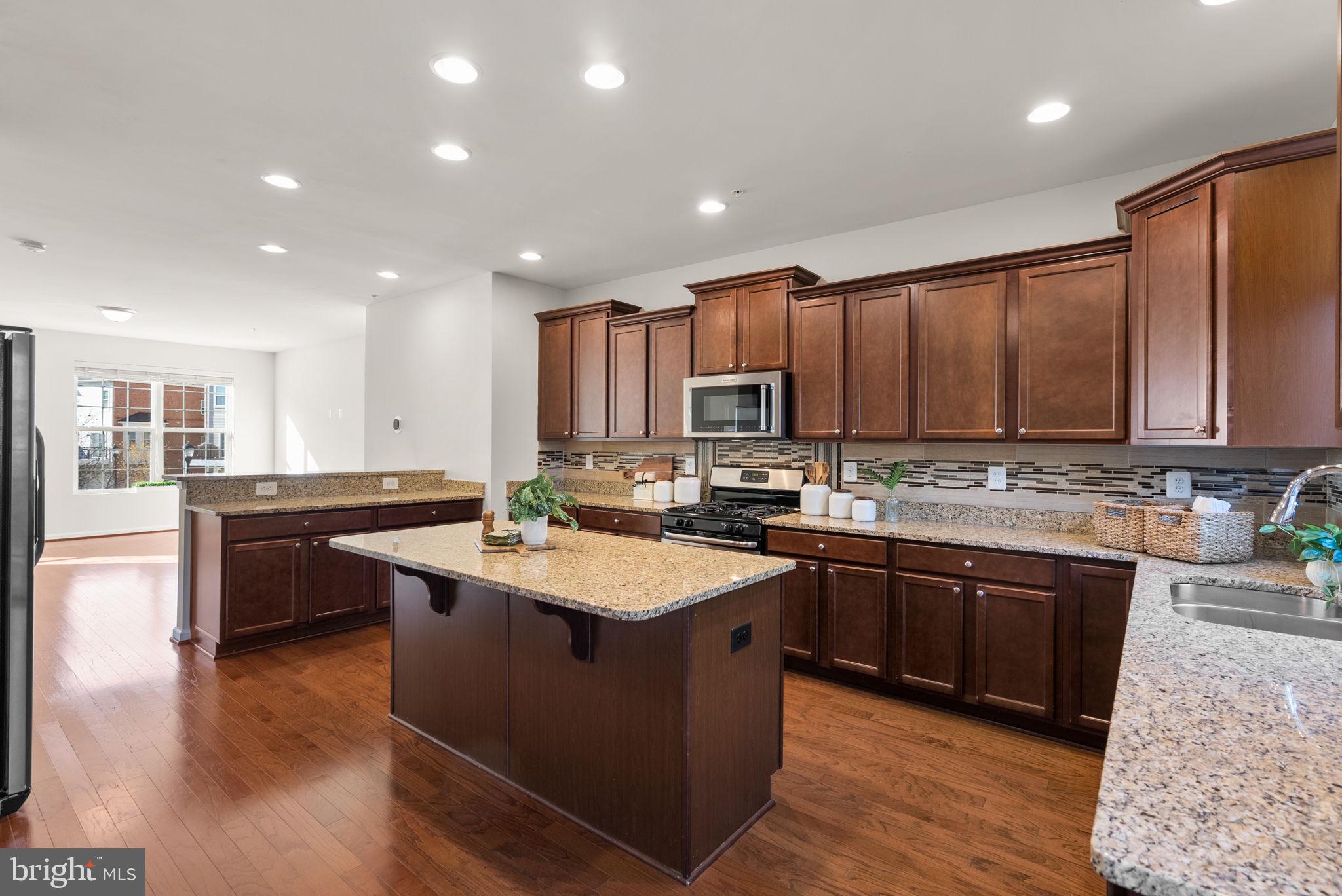 8012 Alchemy Way Elkridge, MD 21075 - Photo 6 of 46 an open kitchen with kitchen island granite countertop wooden cabinets a sink and dishwasher