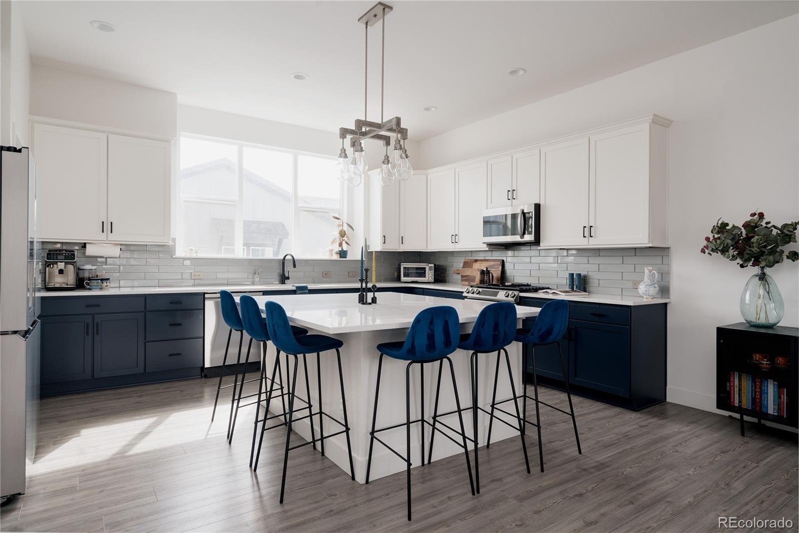 11890 West 52nd Avenue Wheat Ridge, CO 80033 - Photo 11 of 44 a kitchen with stainless steel appliances granite countertop a sink a stove a refrigerator cabinets and a dining table with wooden floor