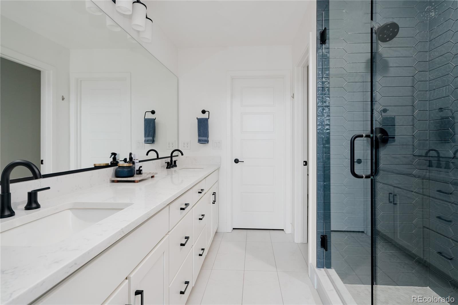 11890 West 52nd Avenue Wheat Ridge, CO 80033 - Photo 30 of 44 a bathroom with a double vanity sink a mirror and shower