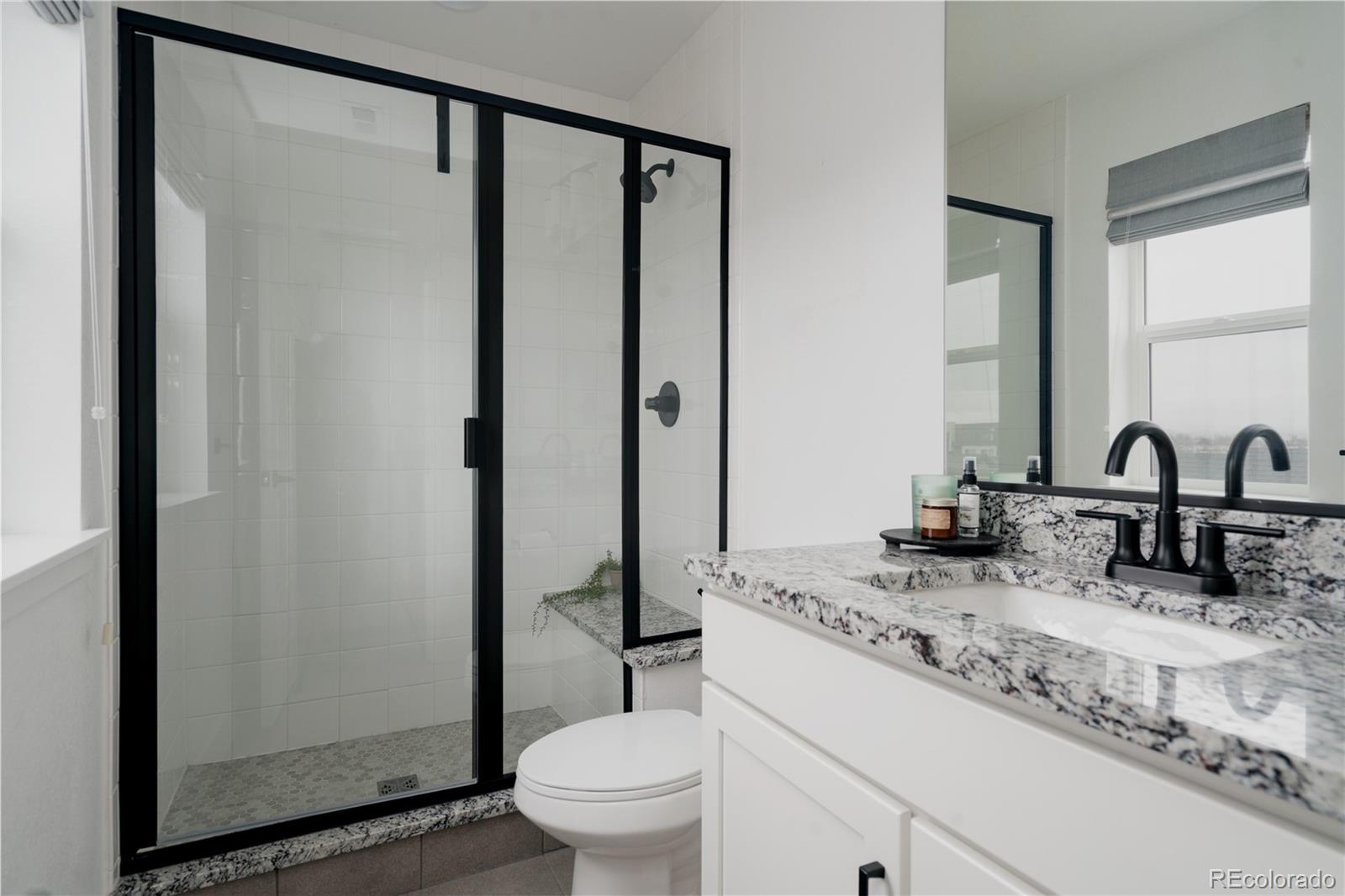 11890 West 52nd Avenue Wheat Ridge, CO 80033 - Photo 36 of 44 a bathroom with a granite countertop sink a toilet and a mirror