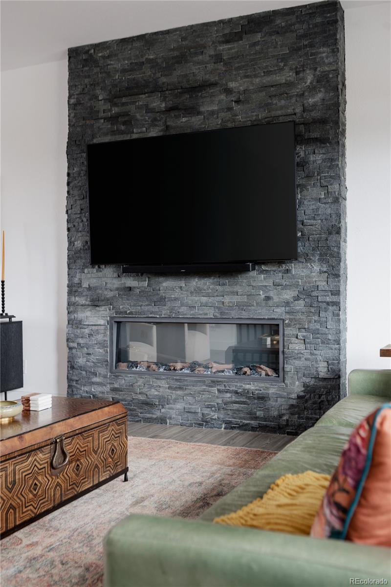11890 West 52nd Avenue Wheat Ridge, CO 80033 - Photo 8 of 44 a living room with furniture a flat screen tv a fireplace and a counter top