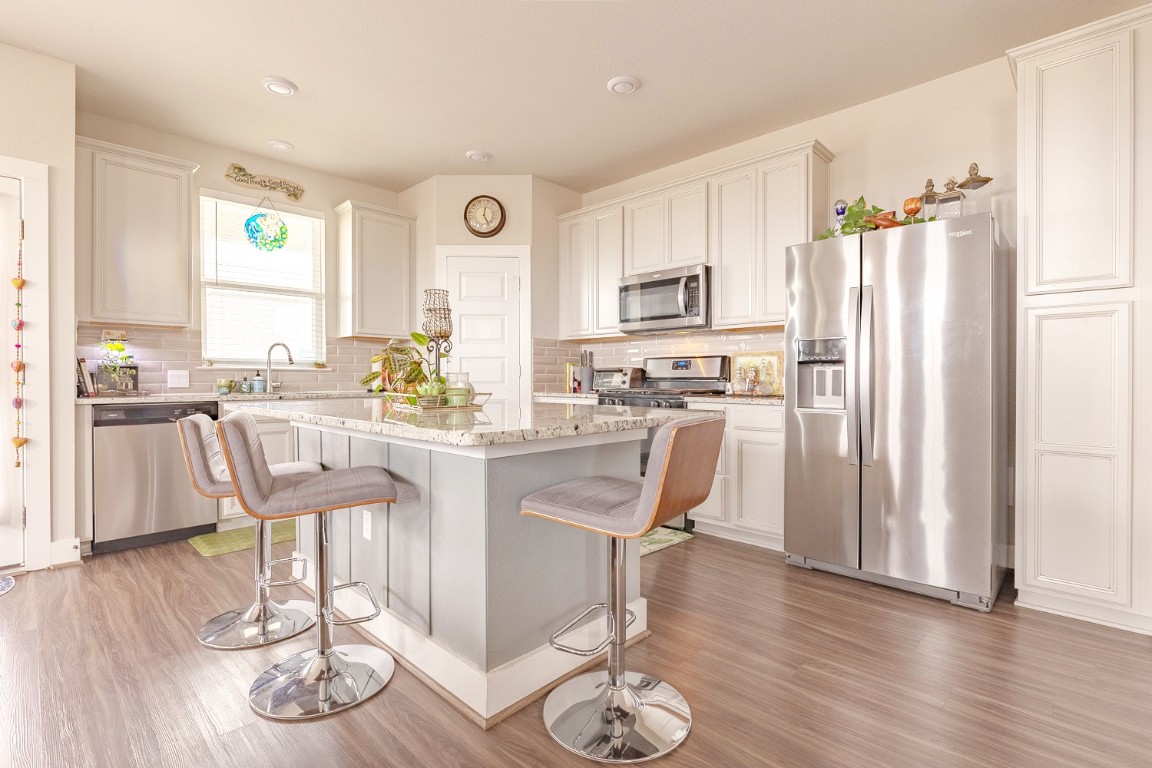 7401 Grand Linden Way, Unit 78 Austin, TX 78744 - Photo 3 of 17 a kitchen with stainless steel appliances granite countertop a refrigerator a stove top oven and a dining table with wooden floor