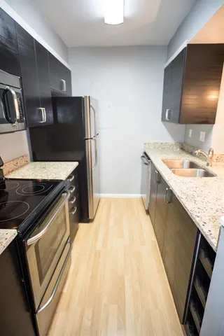 a kitchen with stainless steel appliances granite countertop a sink stove and refrigerator