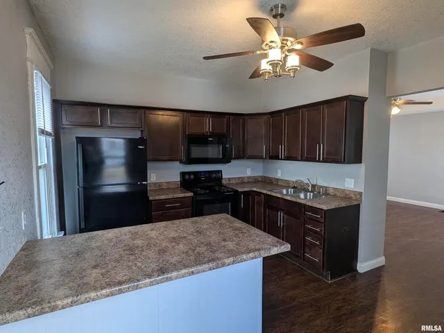 a kitchen with kitchen island granite countertop a sink cabinets and stainless steel appliances