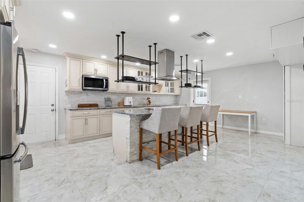 2453 Roberta Street Largo, FL 33771 - Photo 8 of 29 a kitchen with kitchen island a dining table chairs sink and cabinets