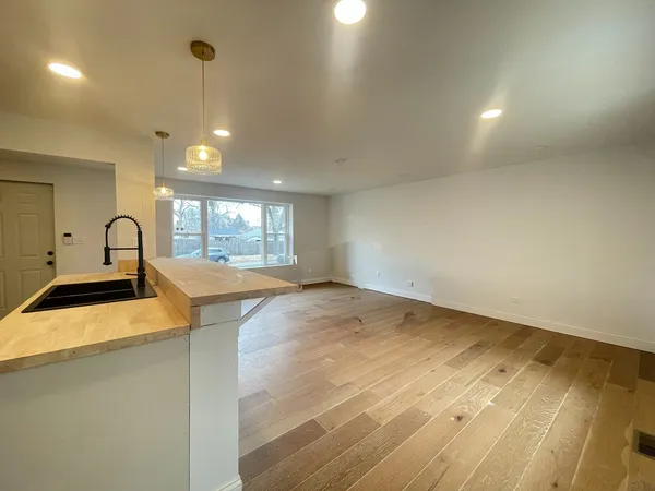 a view of a kitchen with a sink and dishwasher with wooden floor